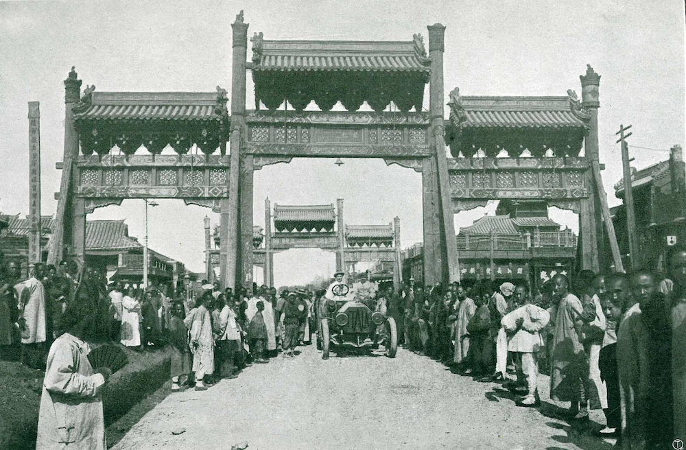 10 juin 1907 : le prince Scipione Borghese et son équipage (le chauffeur Ettore Guizzardi et, à l’arrière, le journaliste Luigi Barzini), sortent de Pékin par la grande porte dans leur Itala 35/45 hp. Face à eux, une seule certitude : 15 000 kilomètres à couvrir pour rallier Paris. Et le risque de ne pas arriver tous en vie.(copyright archives AgrippA-mediA /// Fonds Montén)